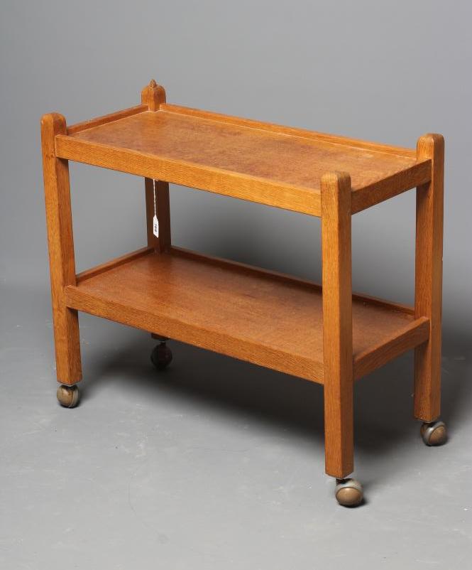 ROBERT THOMPSON - AN OAK TWO TIER TEA TROLLEY on square section uprights with pointed finials Image