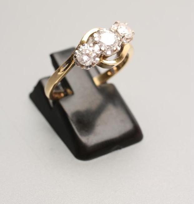 A THREE STONE DIAMOND CROSSOVER RING Image