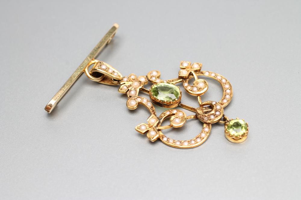 AN EDWARDIAN 9CT GOLD PENDANT of open shield form set with two facet cut peridots and split seed Image