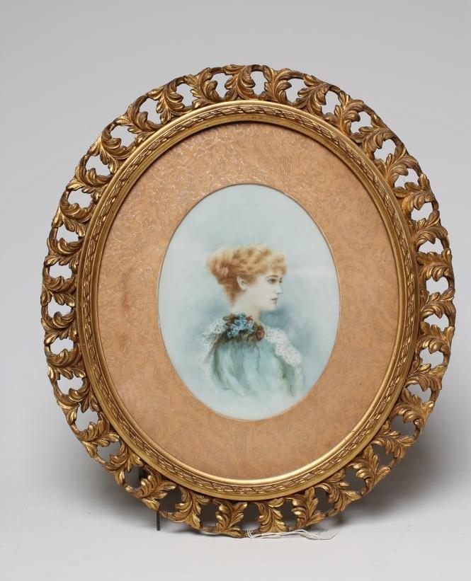 AN EDWARDIAN OPAQUE GLASS OVAL PANEL painted with the half length portrait of a young lady wearing a Image
