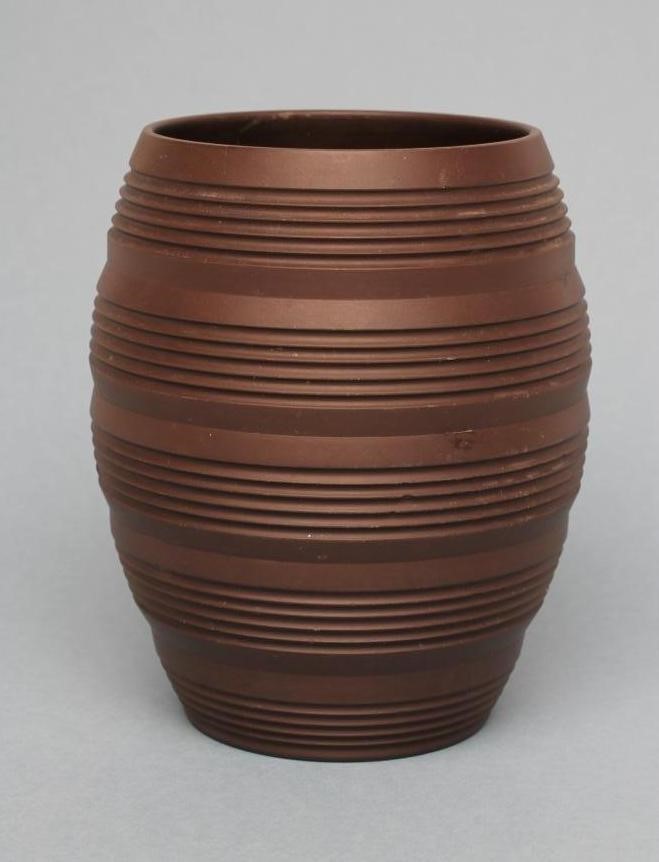 KEITH MURRAY FOR WEDGWOOD - A dark brown basalt barrel vase with five engine turned ribbed bands Image