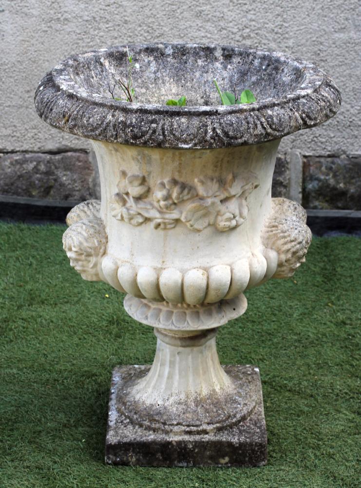 A COMPOSITION STONE URN of half fluted campana form with mask handles and square base Image