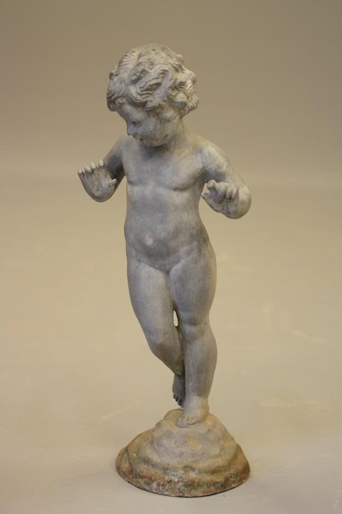 A LEAD FIGURE OF A PUTTO modelled standing on a domed rockwork base Image