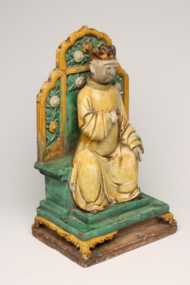 A CHINESE EARTHENWARE FIGURE modelled as a dignitary seated on a flower moulded throne on a stepped Image