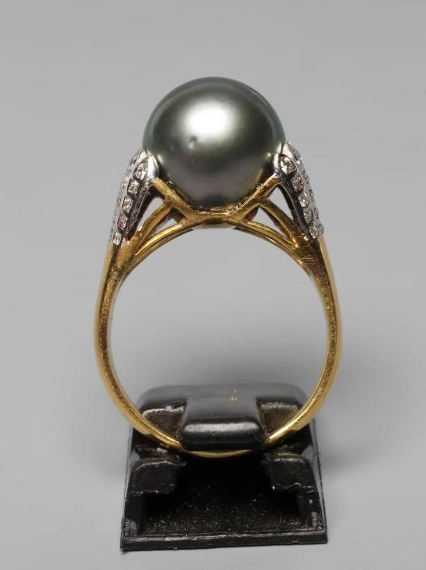A BLACK TAHITIAN PEARL COCKTAIL RING, the pearl set within flared white shoulders set with five sets Image