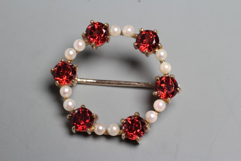 A GARNET AND SEED PEARL CIRCLET BROOCH claw set with six facet cut garnets and twelve pearls to a Image