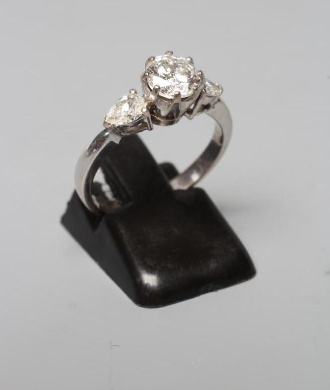 A DIAMOND RING, the central brilliant cut stone of approximately 0.85cts, claw set and flanked by a Image