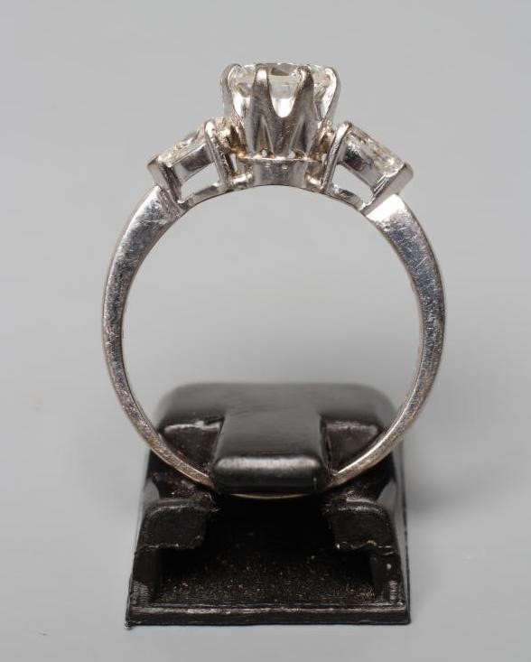 A DIAMOND RING, the central brilliant cut stone of approximately 0.85cts, claw set and flanked by a Image
