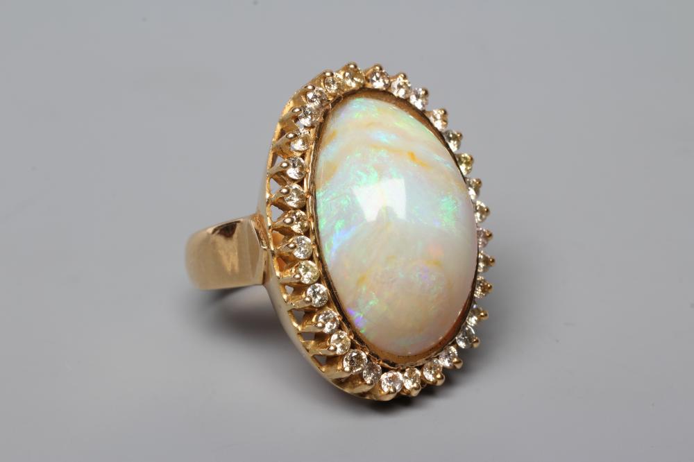 AN OPAL DRESS RING, the oval cabochon polished stone collet set to a border of numerous small Image