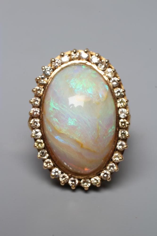 AN OPAL DRESS RING, the oval cabochon polished stone collet set to a border of numerous small Image