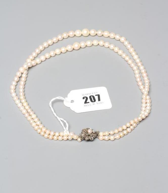 A DOUBLE STRAND OF CULTURED PEARLS with marcasite set silver flower clasp, stamped 935 (Est. plus Image