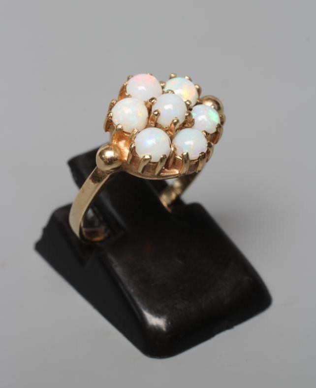 A SEVEN STONE OPAL RING, the circular cabochon polished stones claw set to a plain 9ct gold shank, Image