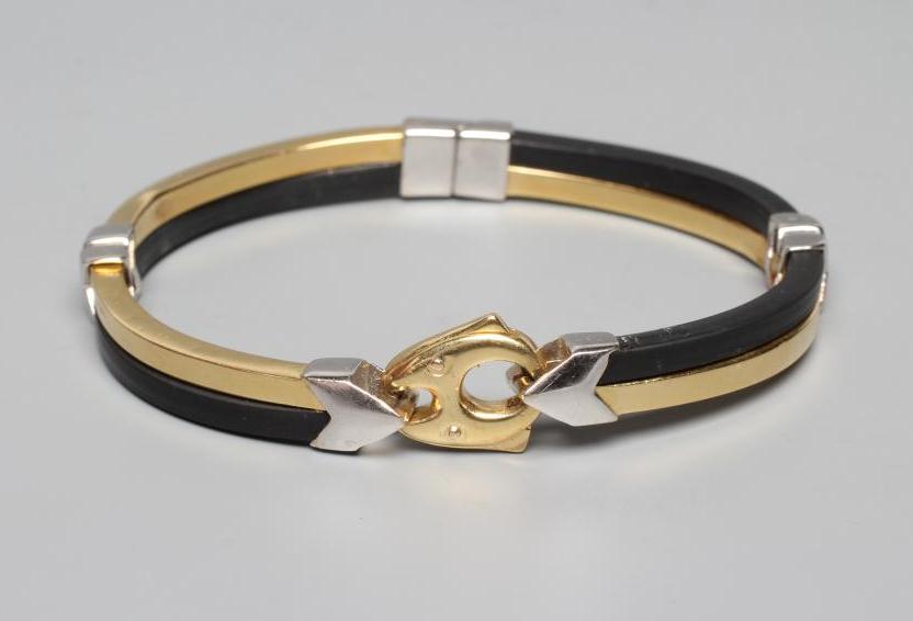 A BARAKA STIFF HINGED BANGLE, the bi-coloured metal stamped 750, with black rubber sections tied by Image