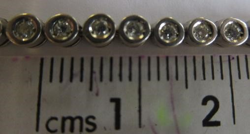 A DIAMOND TENNIS BRACELET, the fifty small round brilliants collet set to a plain white frame Image