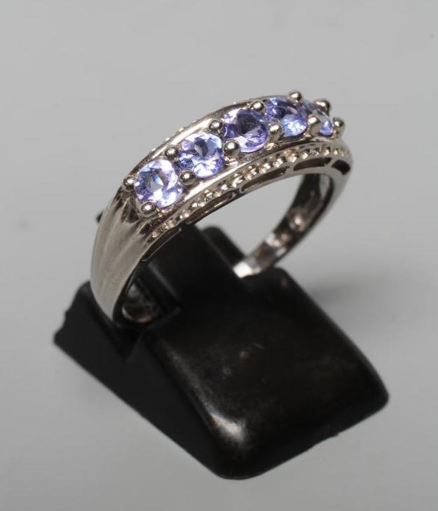 A FIVE STONE TANZANITE RING, the circular facet cut stones point set to rope twist borders and a 9ct Image