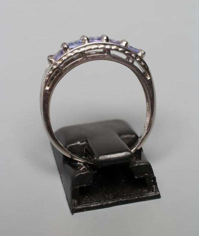 A FIVE STONE TANZANITE RING, the circular facet cut stones point set to rope twist borders and a 9ct Image