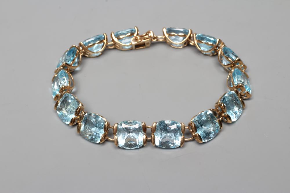A BUE TOPAZ BRACELET, the fourteen cushion cut stones set to a plain link 9ct gold frame with slide Image