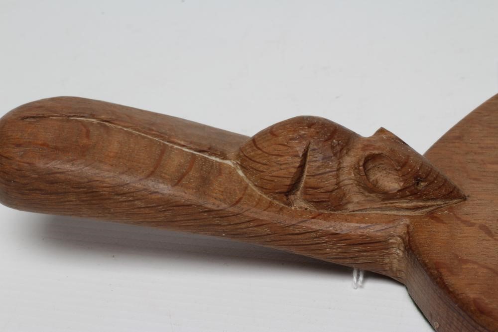 A ROBERT THOMPSON ADZED OAK CHEESE BOARD of oval form, the lug handle with carved mouse trademark in Image