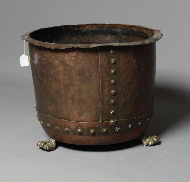 A COPPER LOG BIN, c.1900, of circular form with flared rim and riveted banding, on brass lion paw Image