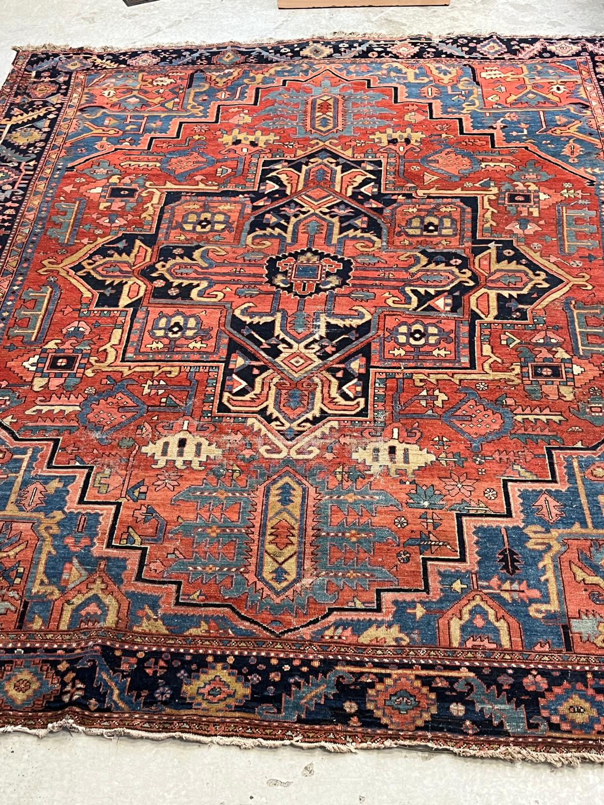 AN HERIZ CARPET, early 20th century, the madder field with large indigo gul and sky blue spandrels, Image