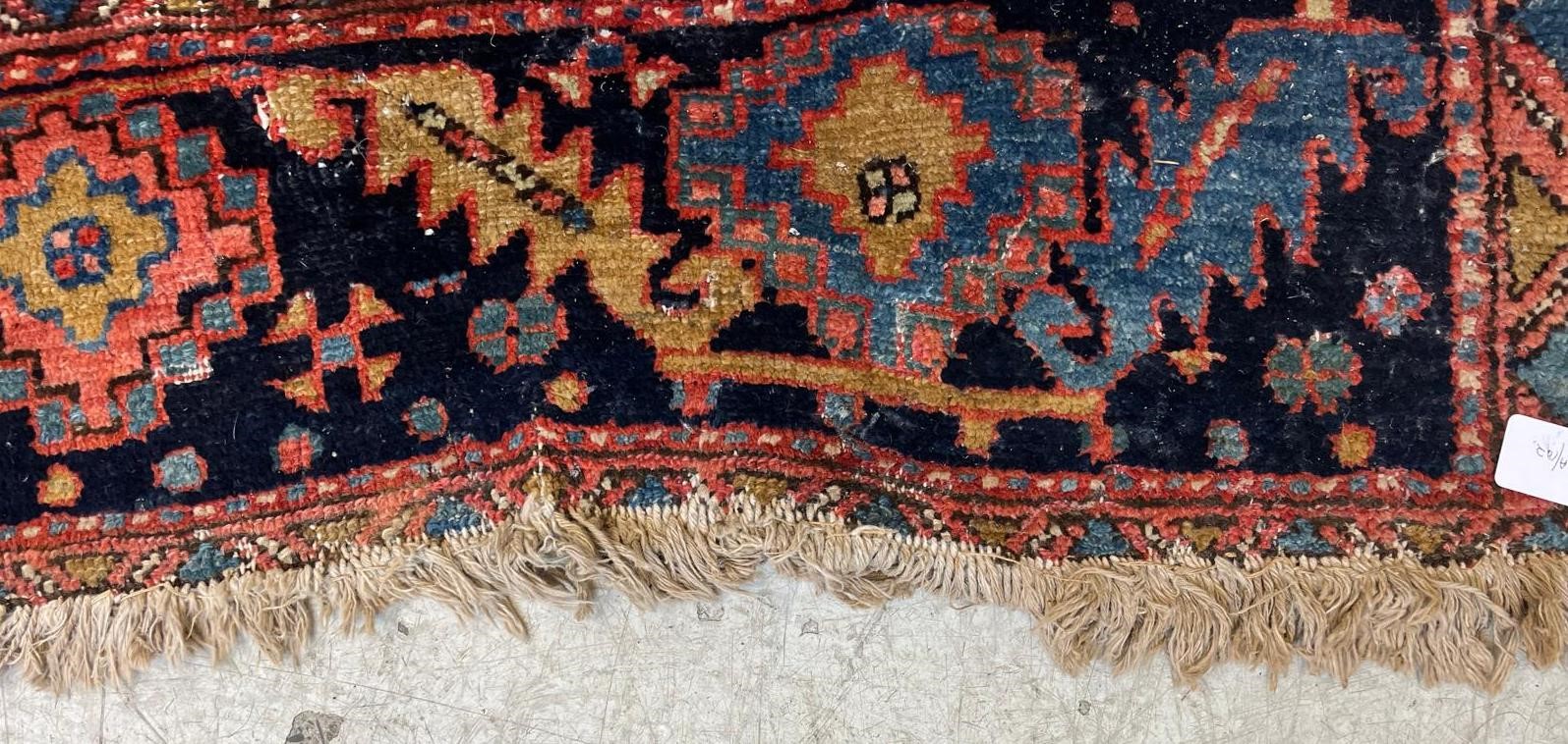 AN HERIZ CARPET, early 20th century, the madder field with large indigo gul and sky blue spandrels, Image