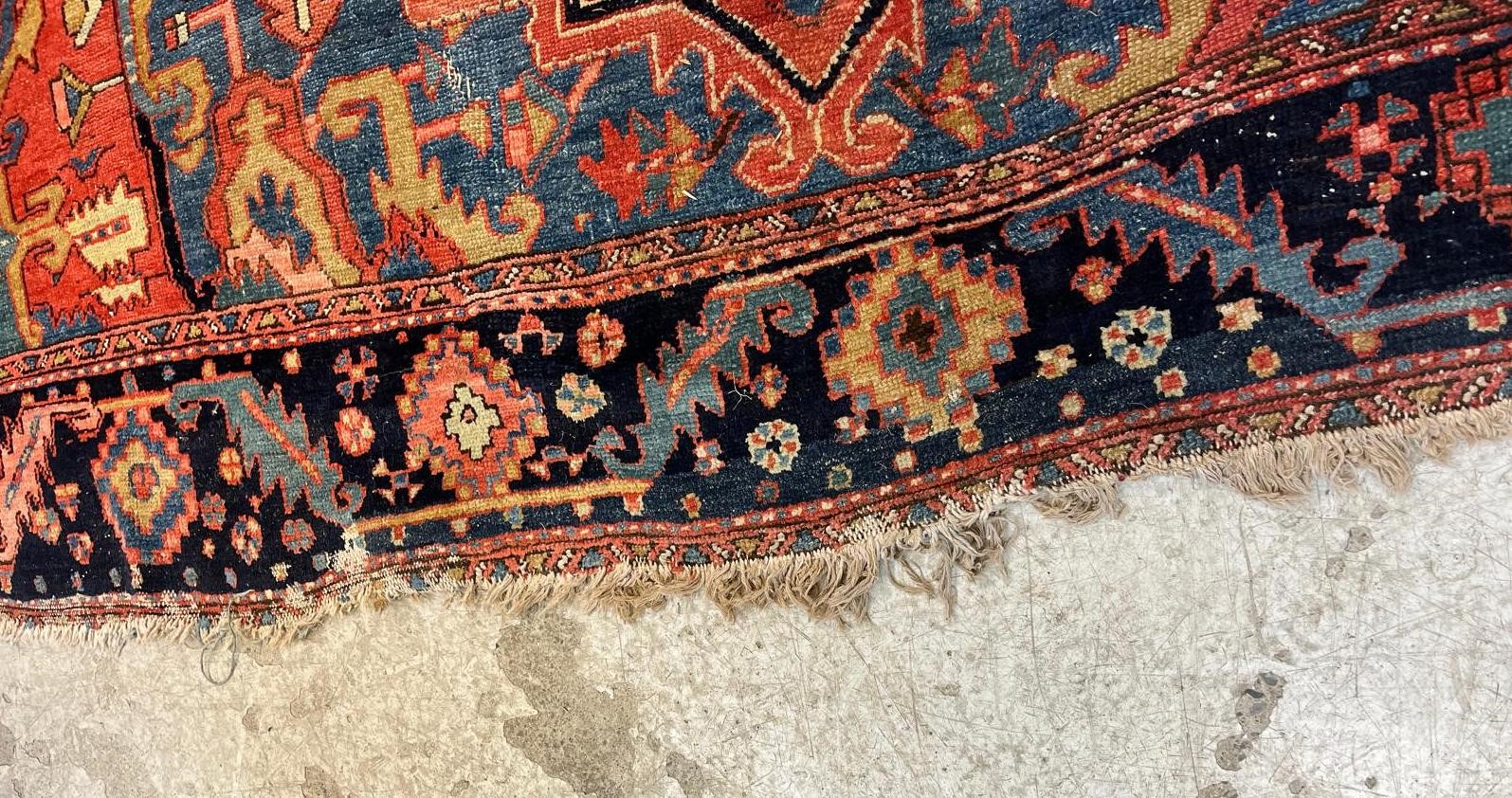 AN HERIZ CARPET, early 20th century, the madder field with large indigo gul and sky blue spandrels, Image