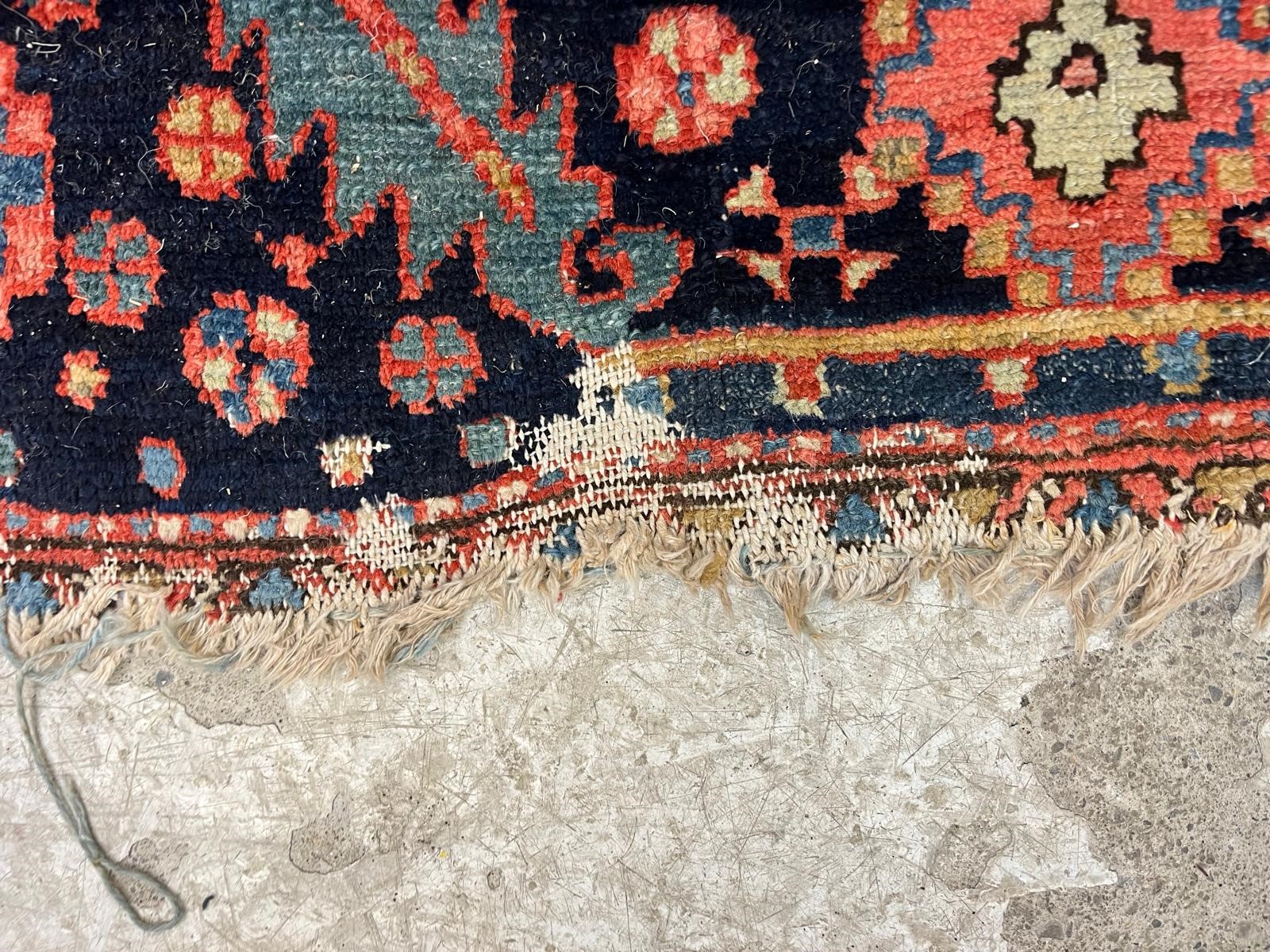 AN HERIZ CARPET, early 20th century, the madder field with large indigo gul and sky blue spandrels, Image