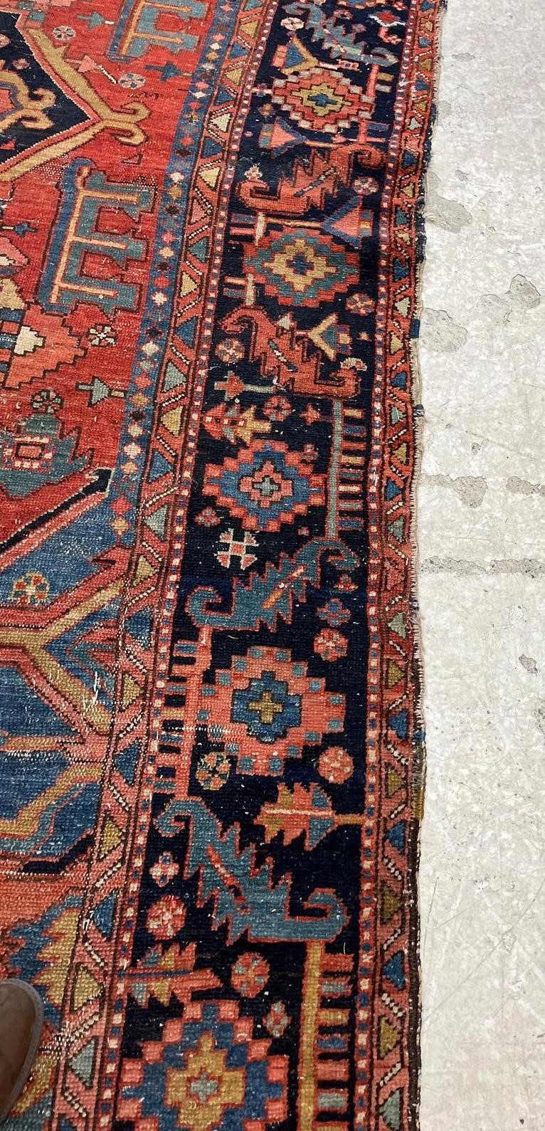 AN HERIZ CARPET, early 20th century, the madder field with large indigo gul and sky blue spandrels, Image