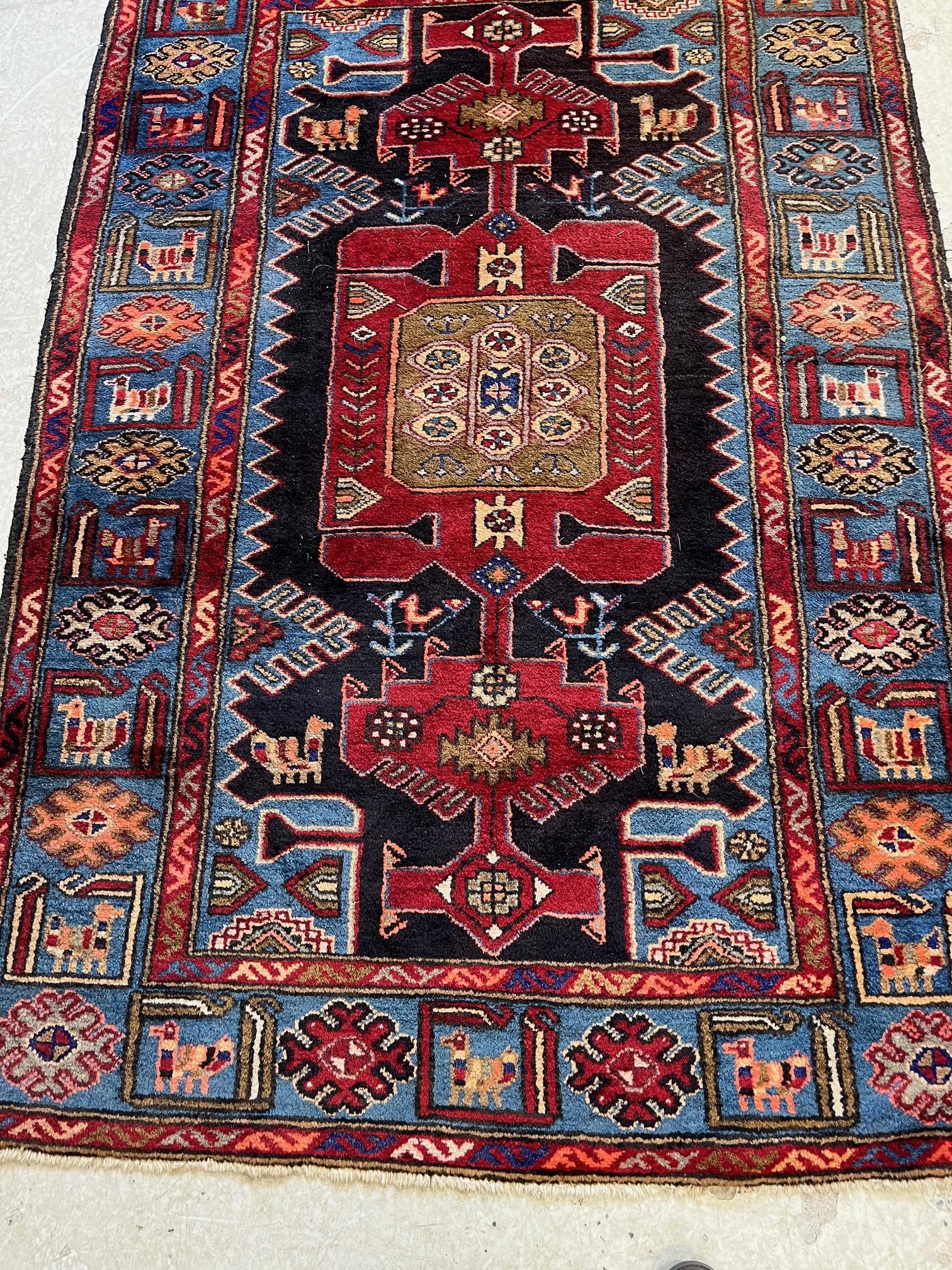 A PERSIAN STYLE WOOL RUG, modern, the black field with large claret red gul and sky blue spandrels, Image