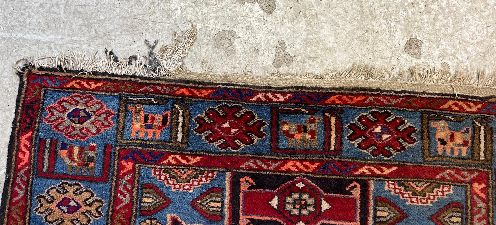 A PERSIAN STYLE WOOL RUG, modern, the black field with large claret red gul and sky blue spandrels, Image