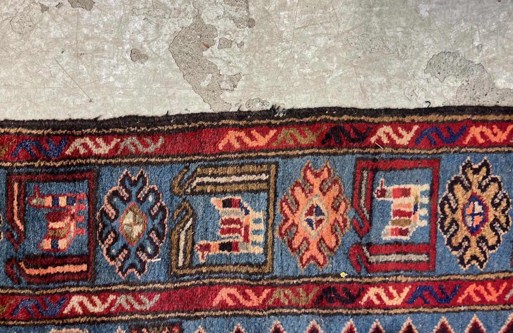 A PERSIAN STYLE WOOL RUG, modern, the black field with large claret red gul and sky blue spandrels, Image