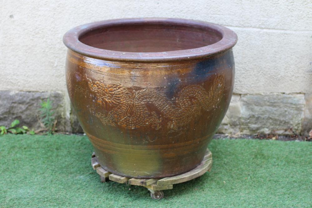 A VERY LARGE SALT GLAZED PLANT POT of tapering form incised with Chinese dragons, resting on a Image