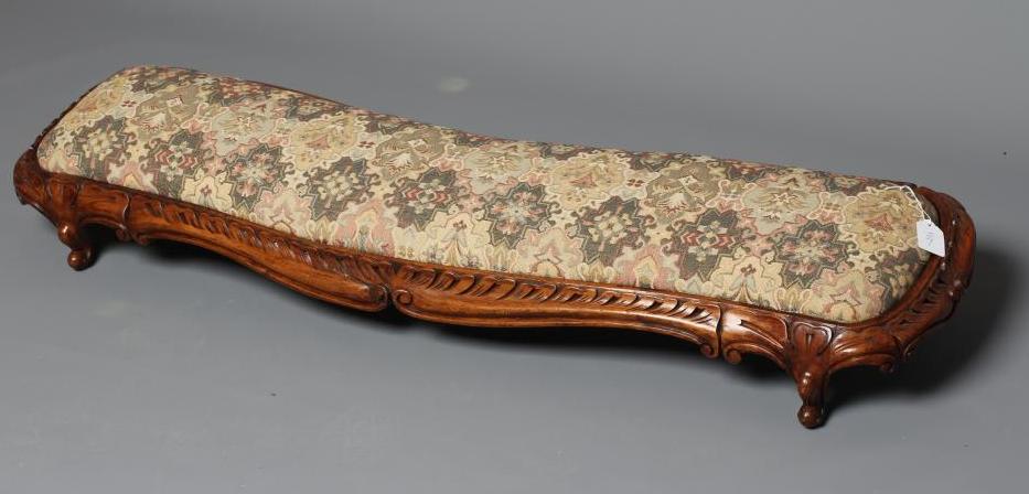 A VICTORIAN CARVED WALNUT FENDER STOOL of serpentine oblong form upholstered in a tapestry weave Image