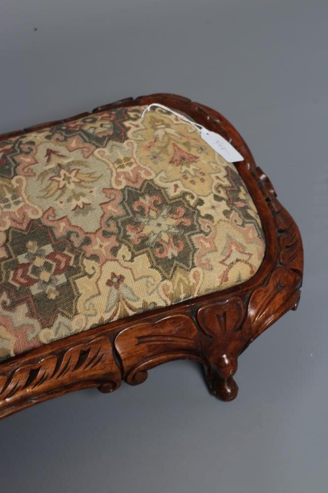 A VICTORIAN CARVED WALNUT FENDER STOOL of serpentine oblong form upholstered in a tapestry weave Image