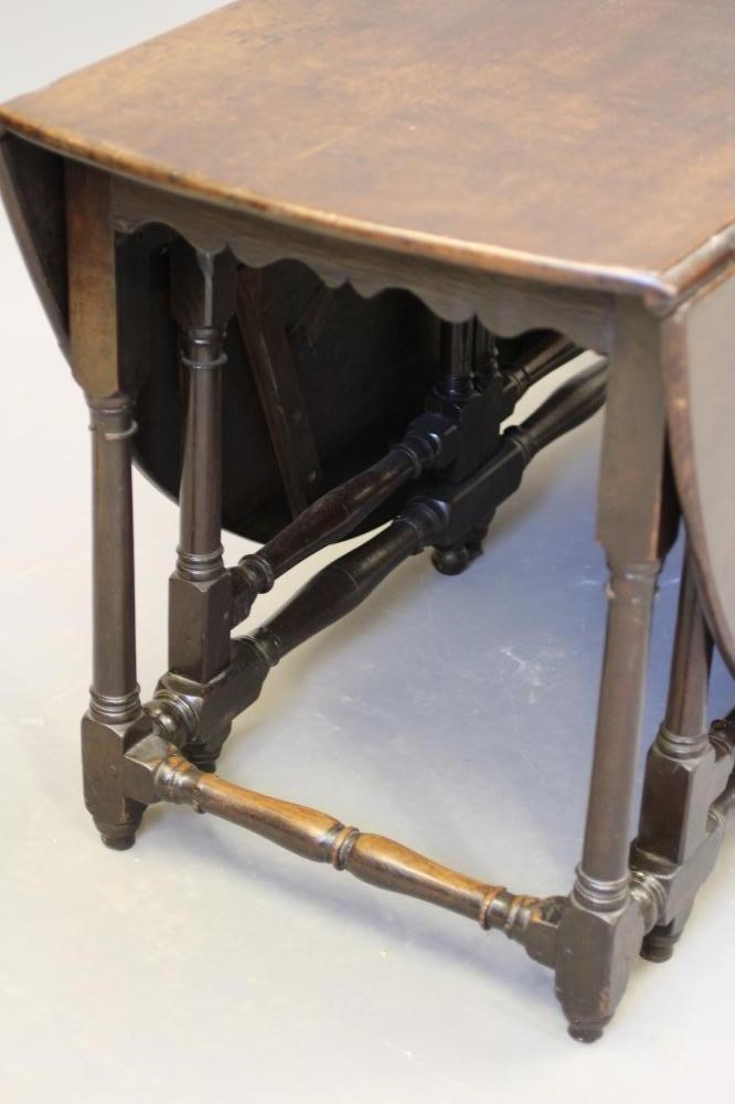AN OAK GATE LEG DINING TABLE, early 18th century, the boarded top raised on columnar legs joined by Image