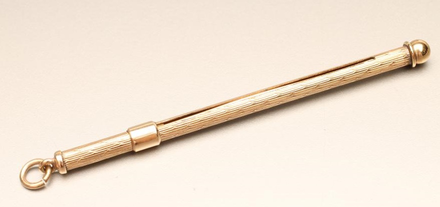 A 9CT GOLD PROPELLING SWIZZLE STICK of plain cylindrical form with engine turning and hanging loop Image