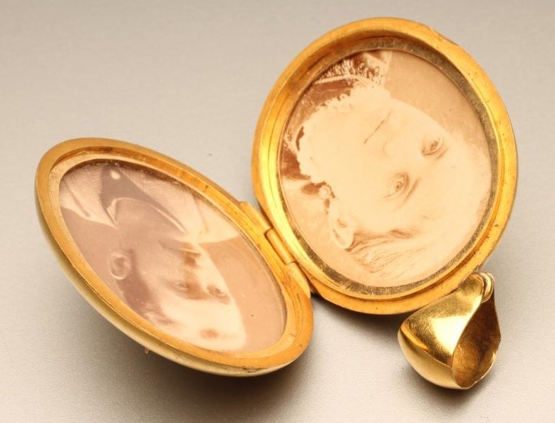 A VICTORIAN GOLD OVAL LOCKET applied with a monogram and enclosing two sepia portrait photographs Image
