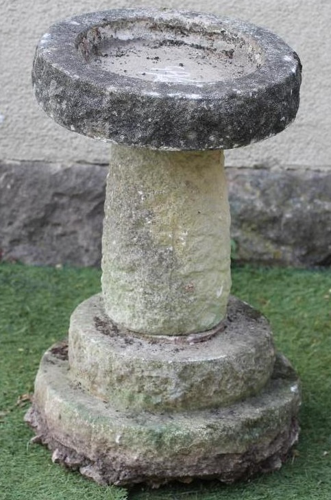 A SANDSTONE BIRD BATH of rough hewn circular form with tapering stem and stepped base (associated) Image