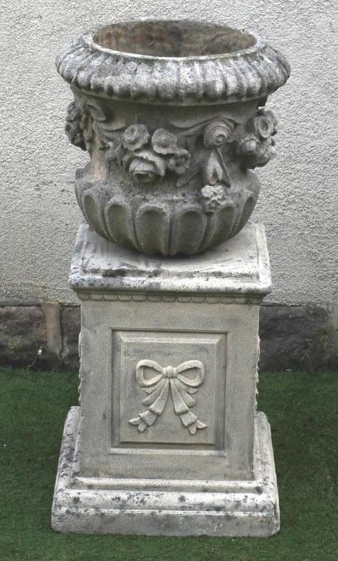 A COMPOSITION STONE URN of waisted half fluted form with ribbon tied floral swags in high relief Image