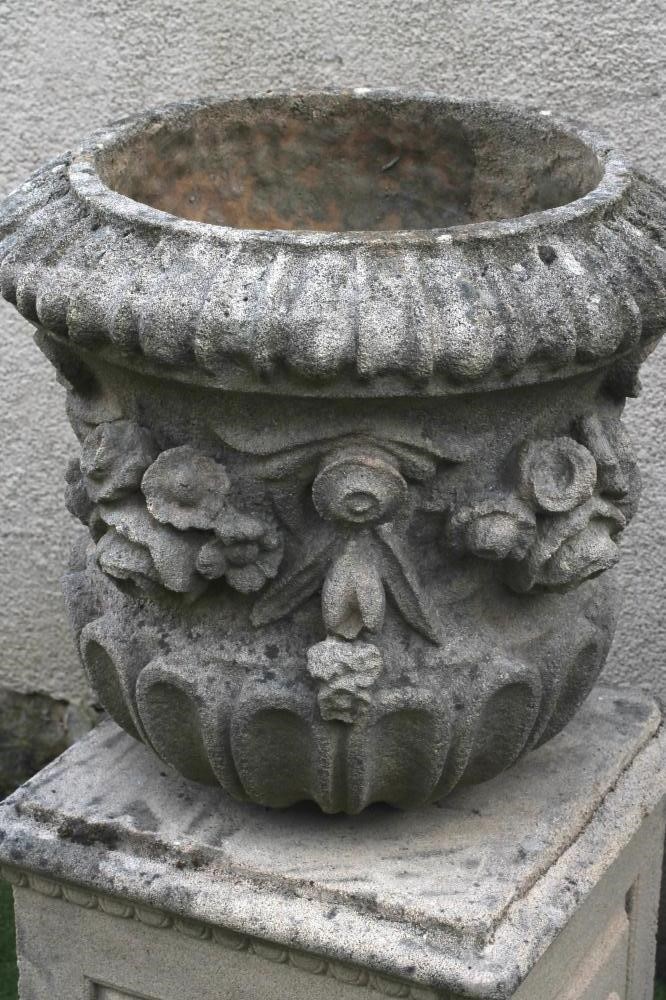 A COMPOSITION STONE URN of waisted half fluted form with ribbon tied floral swags in high relief Image