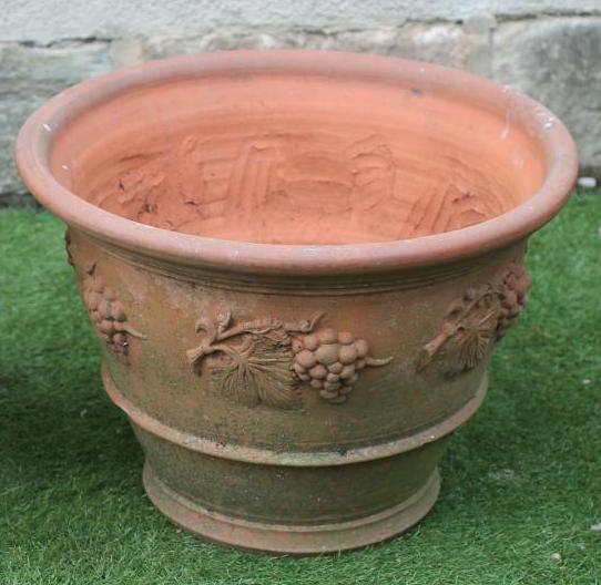 A TERRACOTTA FLOWERPOT of circular tapering form with moulded banding and fruiting vines in relief Image