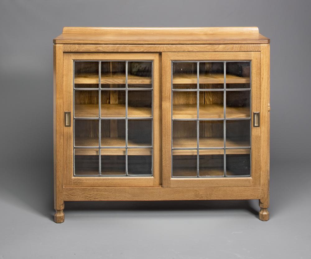 AN ADZED OAK BOOKCASE by Robert Thompson of canted oblong form with ledge back Image