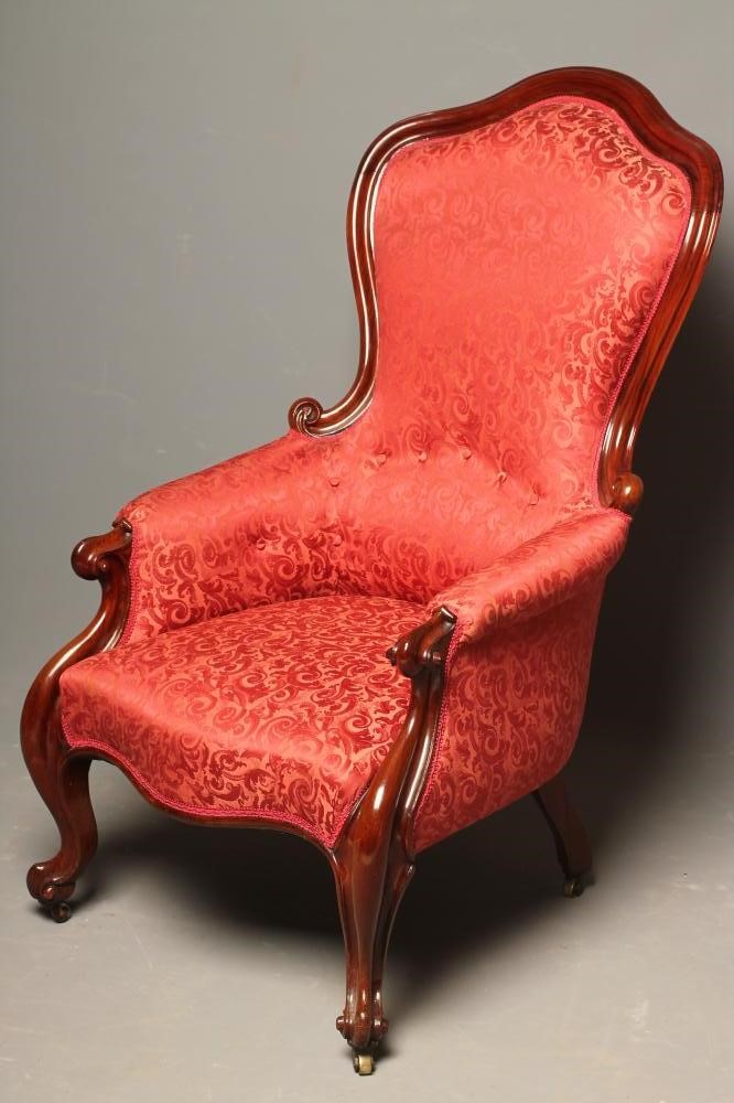 A VICTORIAN WALNUT FRAMED EASY CHAIR of spoonback form upholstered in red brocade Image