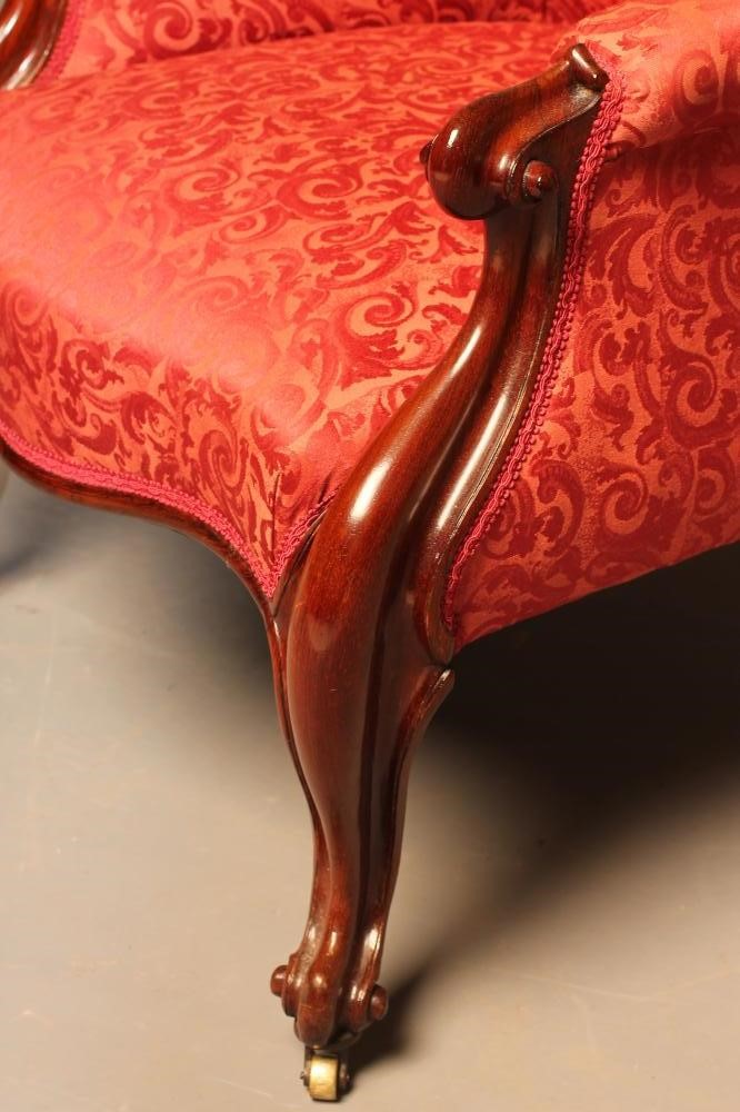 A VICTORIAN WALNUT FRAMED EASY CHAIR of spoonback form upholstered in red brocade Image