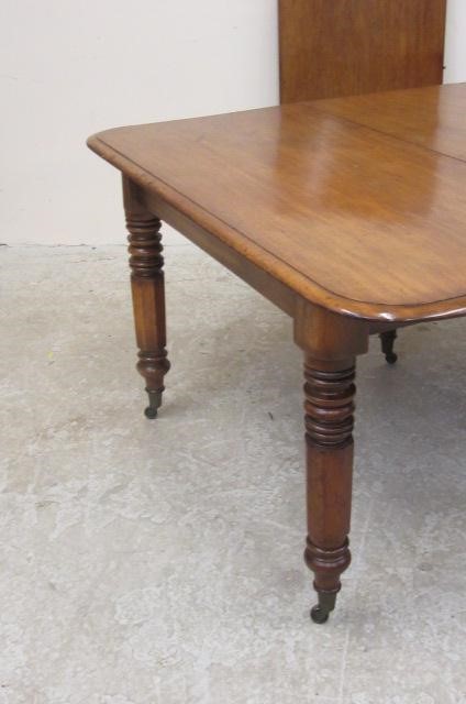 A VICTORIAN MAHOGANY EXTENDING DINING TABLE of rounded oblong form with pull out action and two Image