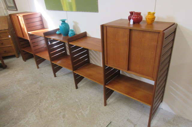 A STAPLES LADDERAX TEAK ROOM UNIT comprising two cupboard units with sliding doors and eight shelves Image