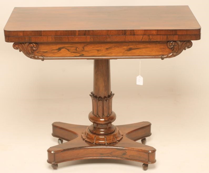 A REGENCY ROSEWOOD FOLDING CARD TABLE of rounded oblong form lined with red baize Image