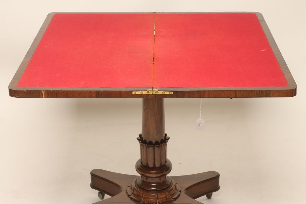 A REGENCY ROSEWOOD FOLDING CARD TABLE of rounded oblong form lined with red baize Image
