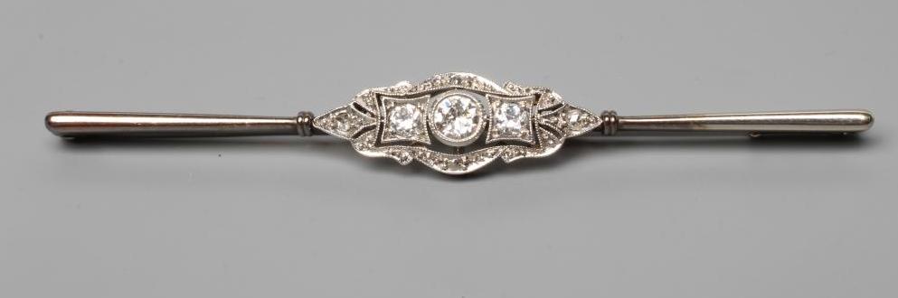 A DIAMOND BAR BROOCH centred by a collet set brilliant cut stone of approximately 0.20cts flanked by Image