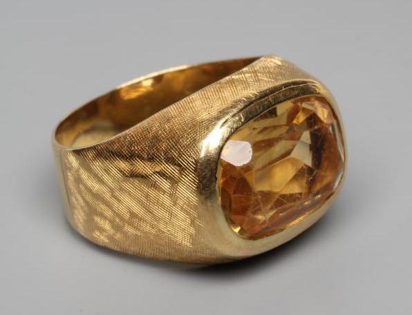 A GENTLEMAN'S DRESS RING, the oval facet cut citrine collet set to criss-cross engraved shoulders Image